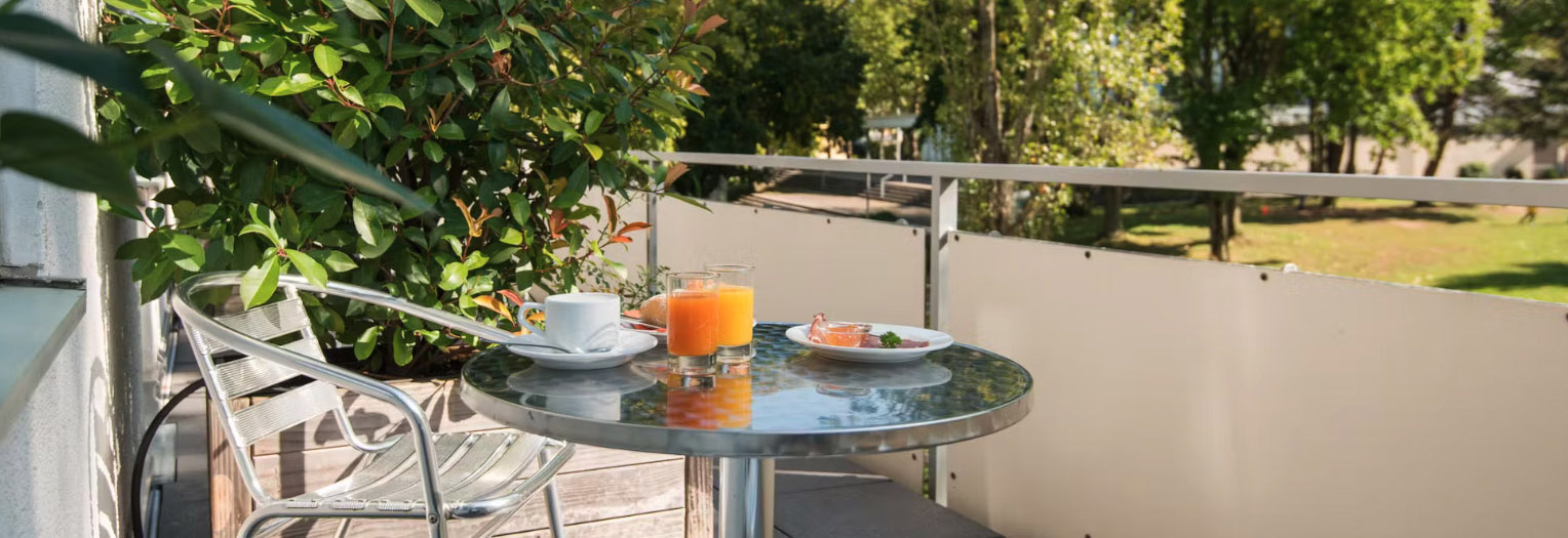 Frühstück auf Balkon mit Kaffee, Säften, Brötchen und Blick ins Grüne