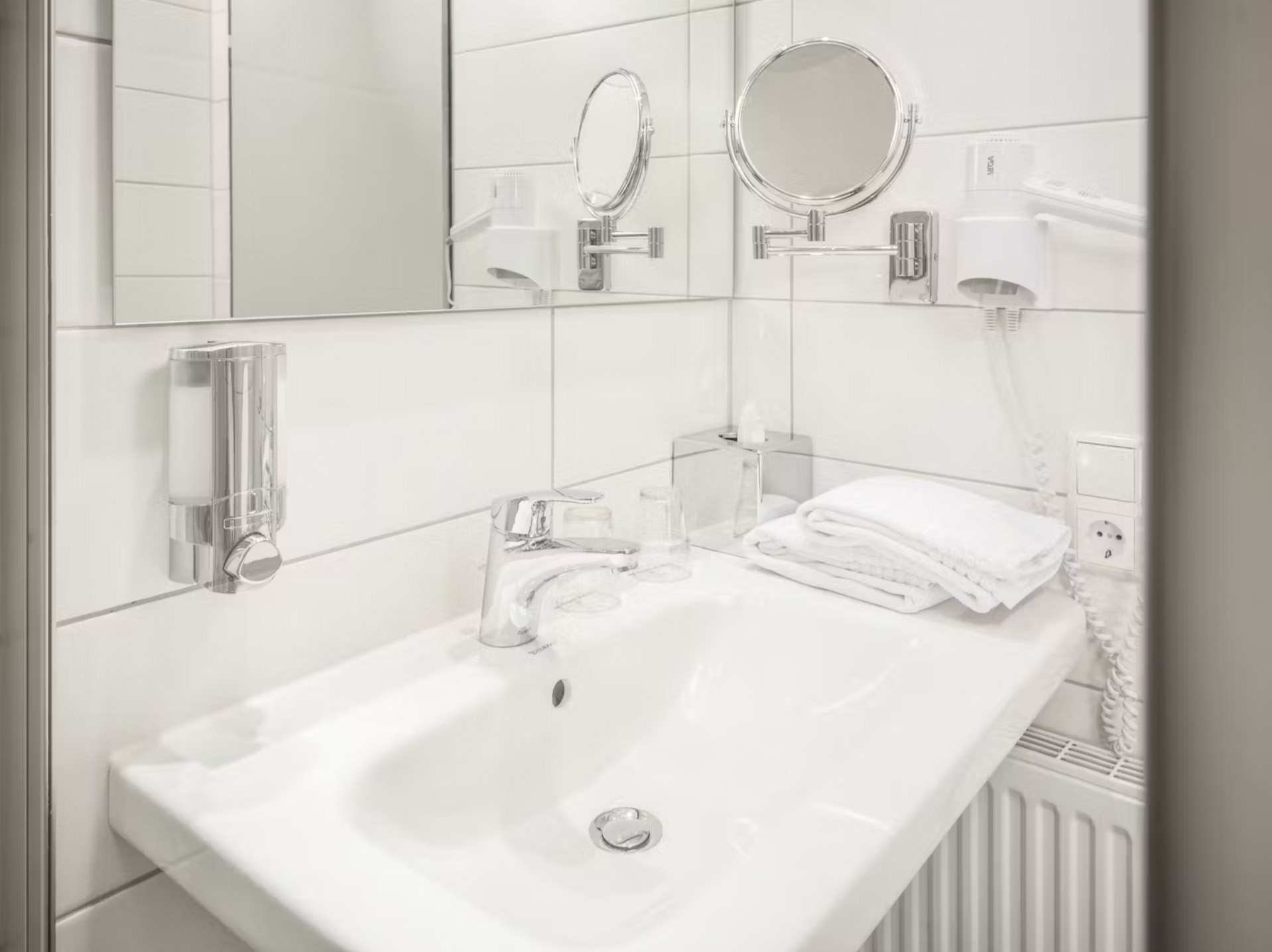 Elegantes Badezimmer mit großem Spiegel, Waschbecken und Föhn.