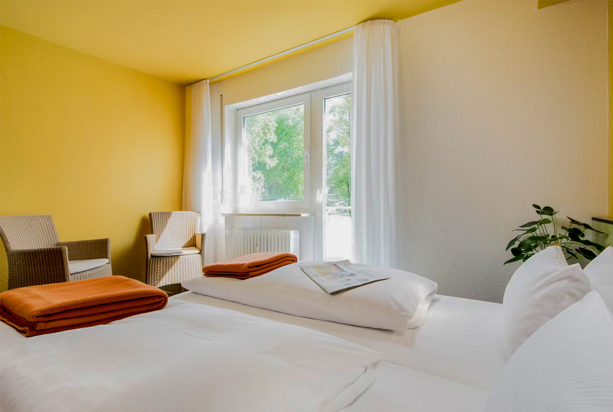 Helles Doppelzimmer, mit Sesseln und Pflanzen