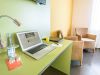 Limettengrüner Tisch mit Getränken und Laptop am Fenster mit Tageslicht