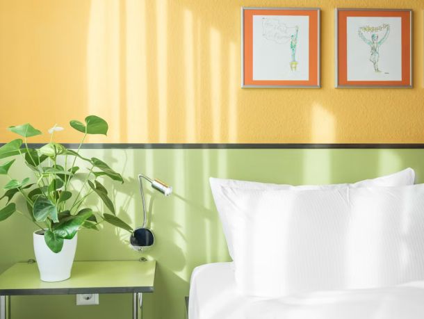 Modernes Einzelzimmer mit limettengrünem Nachttisch, Lampe und gemütlichem Bett