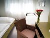 Elegantes Doppelzimmer mit Zustellbett, Rosenvase und Holzhockern