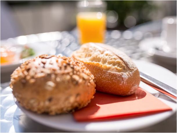 Brötchen auf einem Teller, im Hintergrund ein Glas Orangensaft.